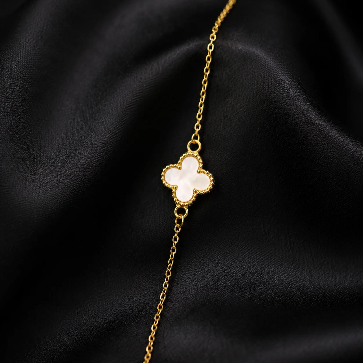 Gold chain bracelet with a white clover centerpiece close-up