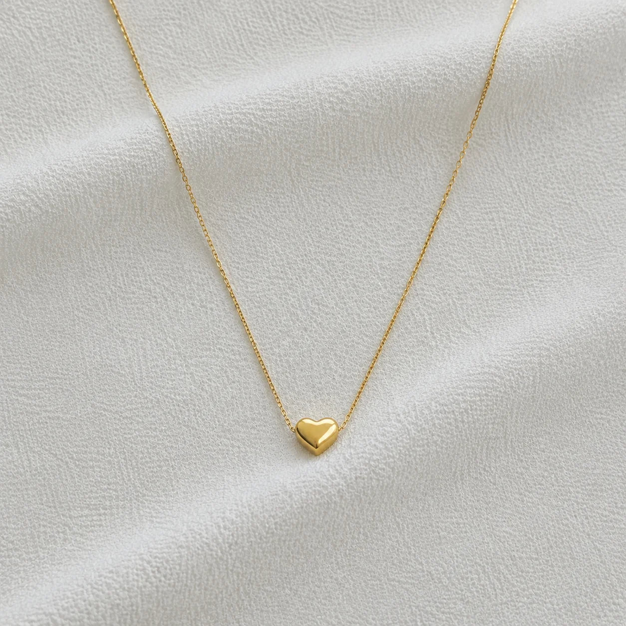 Delicate gold necklace with small heart pendant close-up