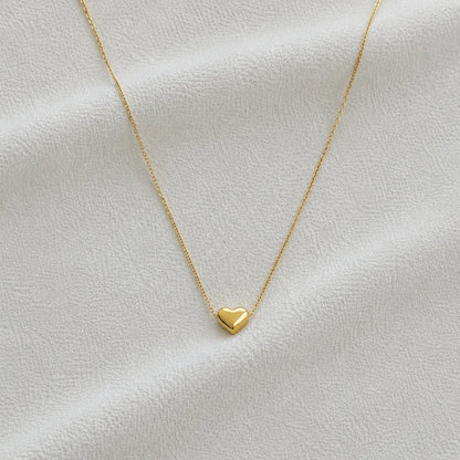 Delicate gold necklace with small heart pendant close-up