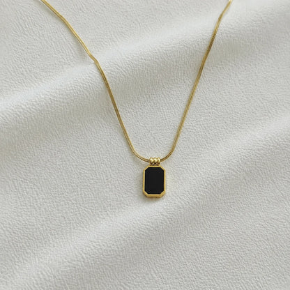 Gold snake-chain necklace with black rectangular pendant close-up
