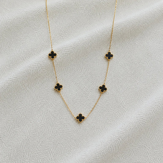 Gold necklace with five black clover stations close-up